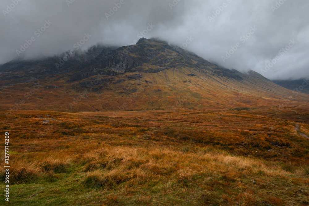 Dramatic peaks and misty valleys define Glen Coe, Scotland’s iconic Highland landscape. Golden light dances on rugged slopes, creating a scene of wild, untamed beauty.