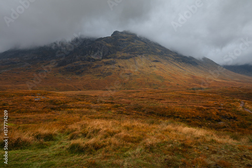 Obraz na płótnie Dramatic peaks and misty valleys define Glen Coe, Scotland’s iconic Highland landscape. Golden light dances on rugged slopes, creating a scene of wild, untamed beauty. w salonie