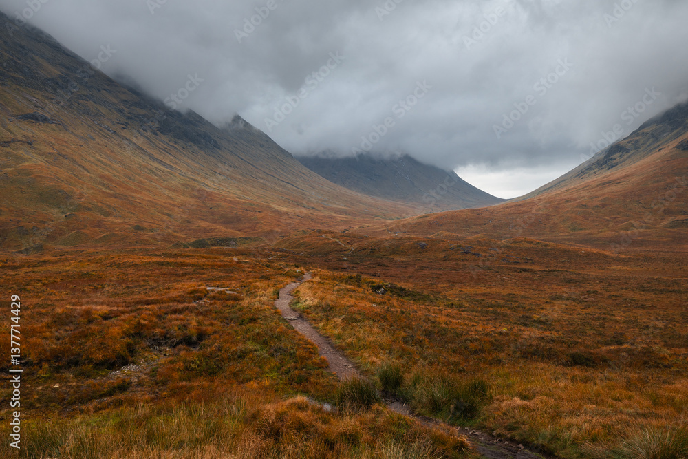 Dramatic peaks and misty valleys define Glen Coe, Scotland’s iconic Highland landscape. Golden light dances on rugged slopes, creating a scene of wild, untamed beauty.