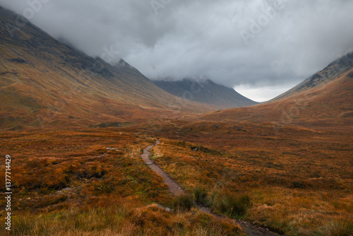 Obraz na płótnie Dramatic peaks and misty valleys define Glen Coe, Scotland’s iconic Highland landscape. Golden light dances on rugged slopes, creating a scene of wild, untamed beauty. w salonie