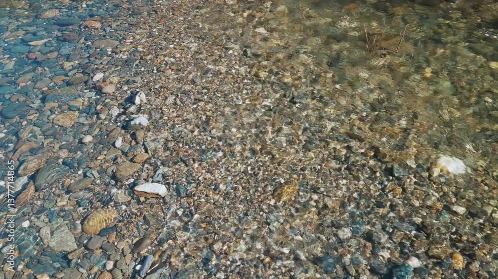 Clear river water over a rocky bottom with sun reflections Clear river water over a rocky bottom with sun reflections