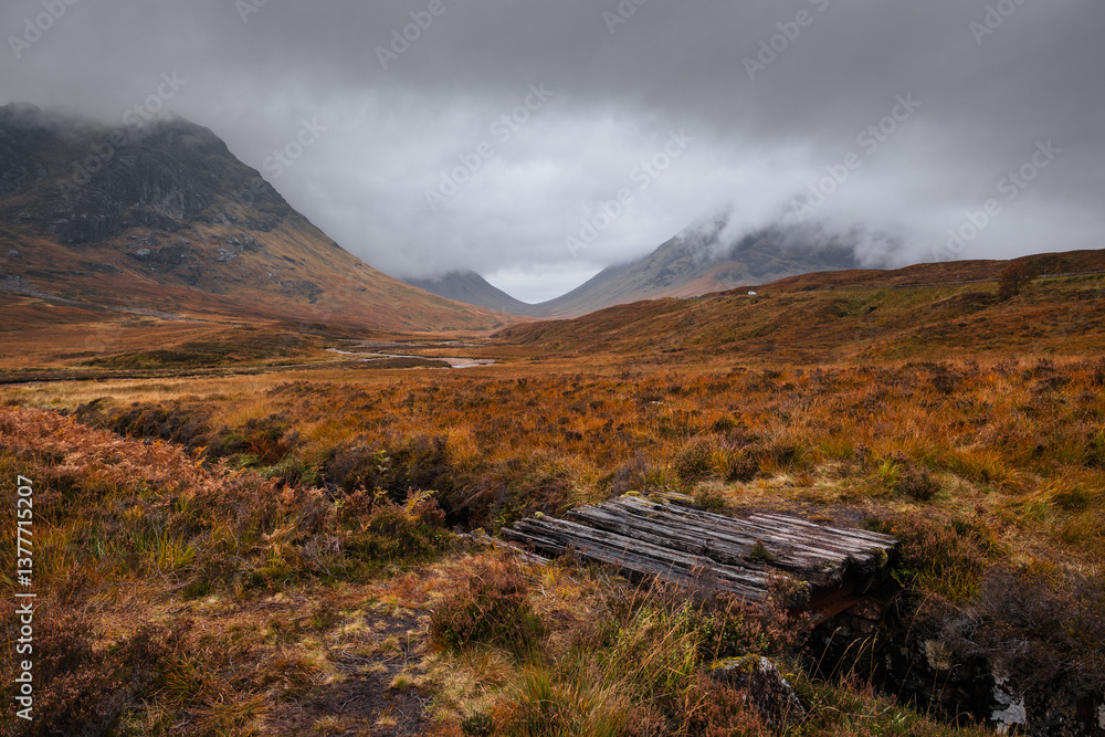 Dramatic peaks and misty valleys define Glen Coe, Scotland’s iconic Highland landscape. Golden light dances on rugged slopes, creating a scene of wild, untamed beauty.