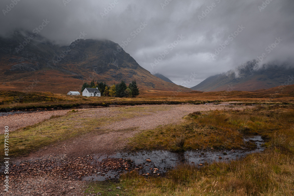 Dramatic peaks and misty valleys define Glen Coe, Scotland’s iconic Highland landscape. Golden light dances on rugged slopes, creating a scene of wild, untamed beauty.