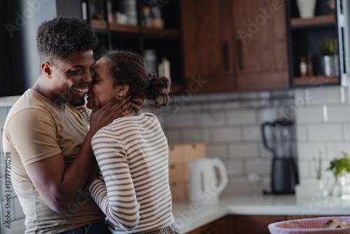 Canvas Print Happy couple sharing an affectionate moment in a modern kitchen, smiling and embracing with love and joy