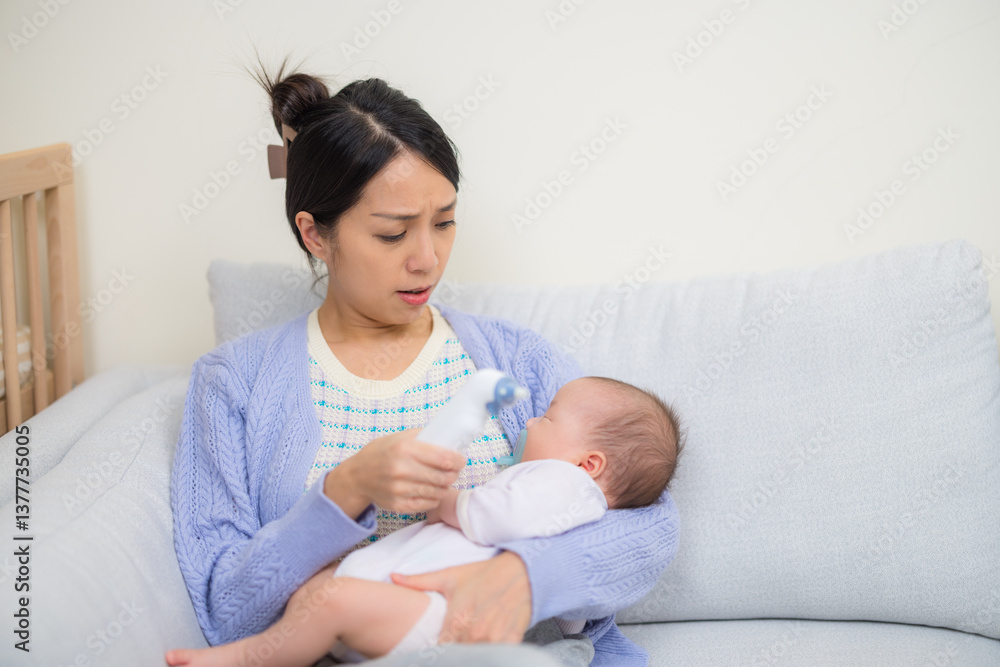 Mother using ear thermometer to check baby fever