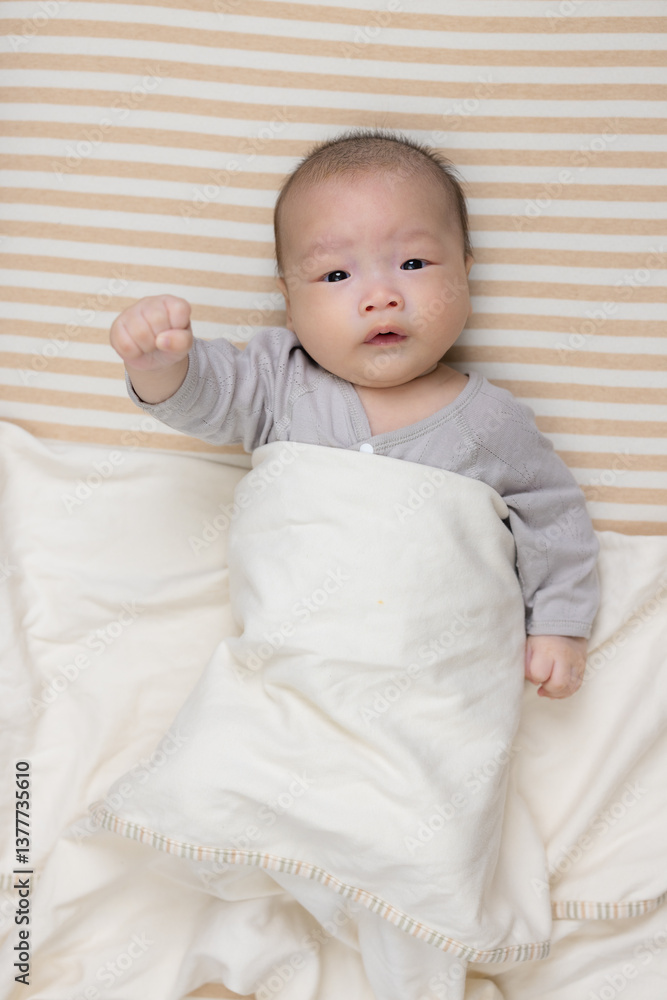 Adorable baby with tiny hands in bed