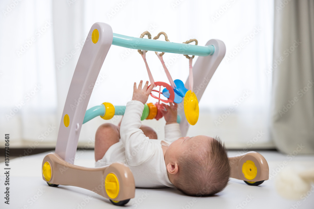 Infant Lying On Play Mat In Baby Gym At Home