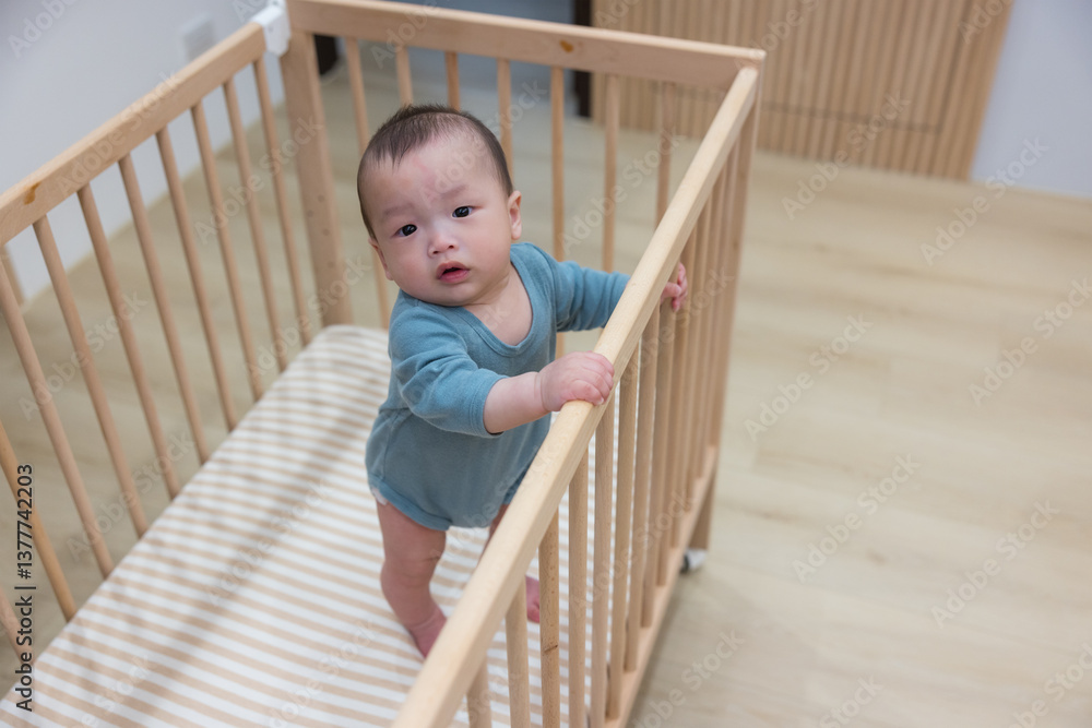 Cute baby standing inside wooden crib