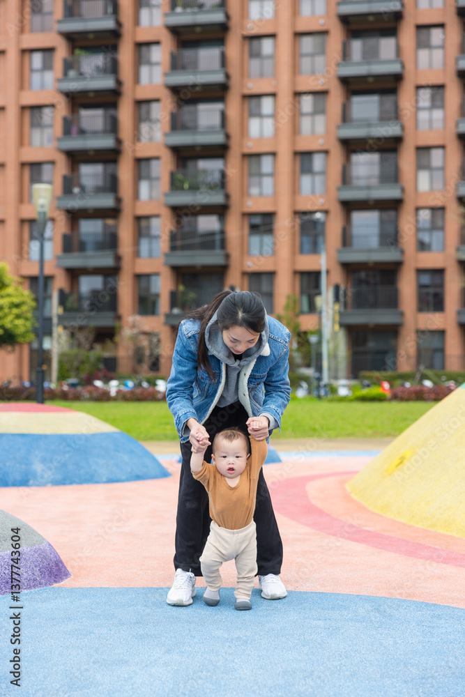 Mother helping baby walk at playground