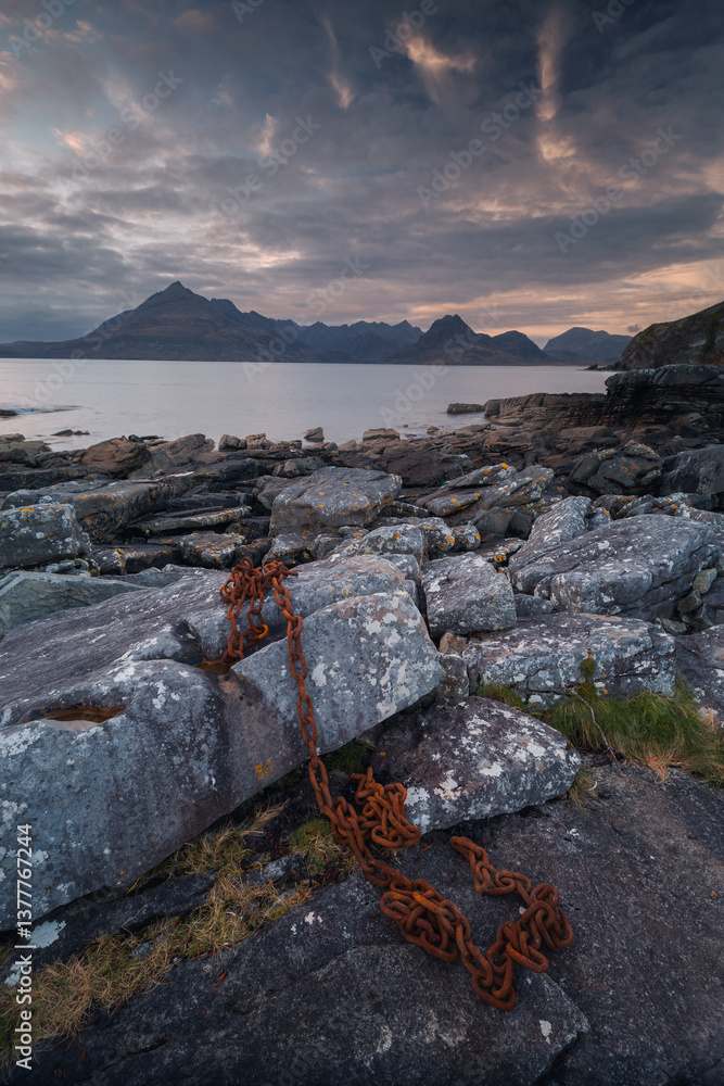 Dramatic waves crash against Elgol’s rugged coast, with the Cuillin Mountains rising in the misty distance. Autumn’s golden light enhances this wild, untamed beauty.