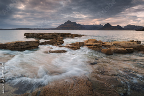 Obraz na płótnie Dramatic waves crash against Elgol’s rugged coast, with the Cuillin Mountains rising in the misty distance. Autumn’s golden light enhances this wild, untamed beauty. w salonie