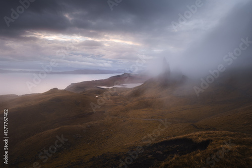 Obraz na płótnie The Old Man of Storr emerges from autumn mist, its towering pinnacles glowing in golden morning light. A mystical, otherworldly Highland scene. w salonie