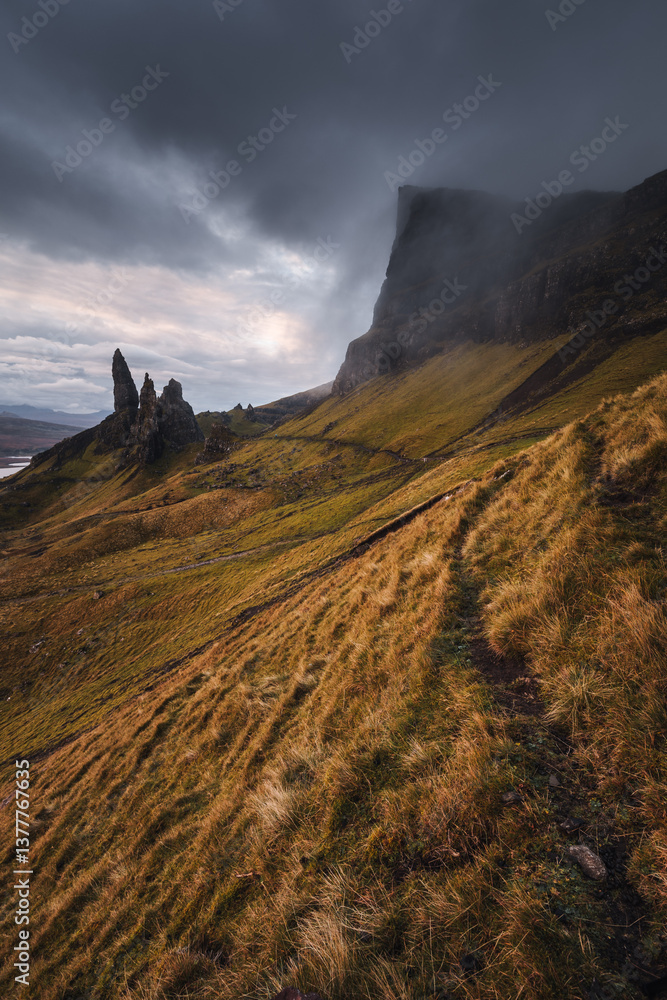 The Old Man of Storr emerges from autumn mist, its towering pinnacles glowing in golden morning light. A mystical, otherworldly Highland scene.