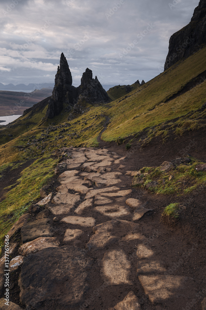The Old Man of Storr emerges from autumn mist, its towering pinnacles glowing in golden morning light. A mystical, otherworldly Highland scene.