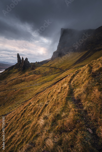 Obraz na płótnie The Old Man of Storr emerges from autumn mist, its towering pinnacles glowing in golden morning light. A mystical, otherworldly Highland scene. w salonie