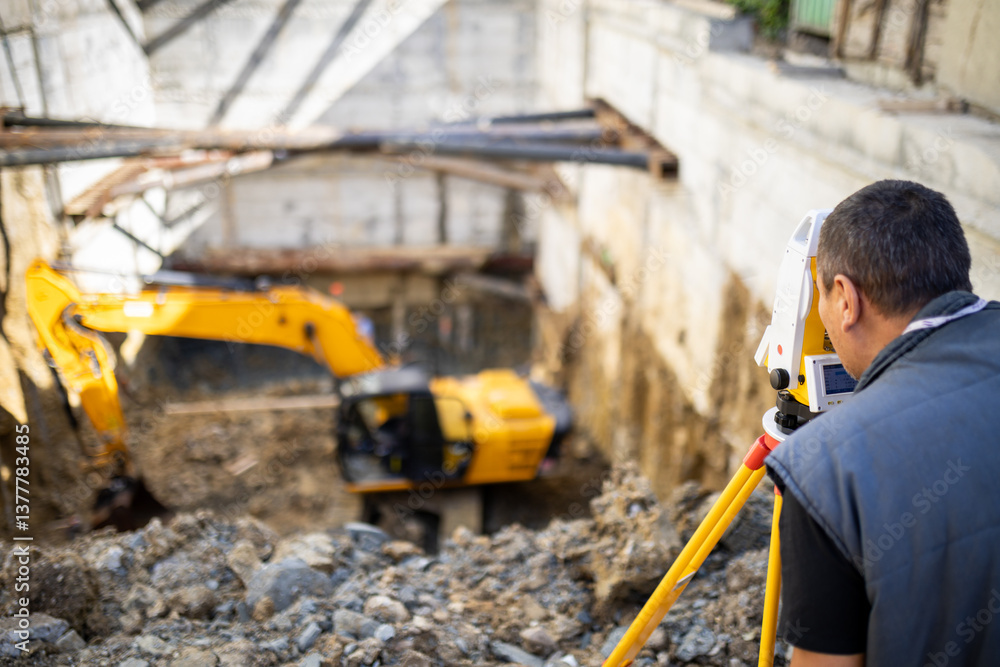 Fototapeta premium Construction worker surveying site with machinery in background at early morning light