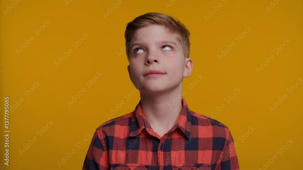 Boy Looking Up Expressing Disbelief on Yellow Background Boy Looking Up Expressing Disbelief on Yellow Background