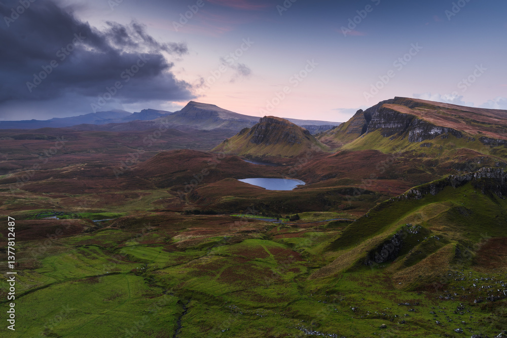 Autumn light bathes the Quiraing on Skye, casting long shadows over its dramatic cliffs and rolling hills. The landscape glows with golden hues, a breathtaking Highland scene.