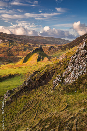 Obraz na płótnie Autumn light bathes the Quiraing on Skye, casting long shadows over its dramatic cliffs and rolling hills. The landscape glows with golden hues, a breathtaking Highland scene. w salonie
