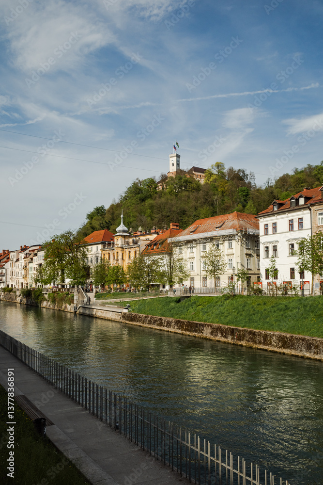 Fototapeta premium Scenic view of Ljubljana, with a river, buildings, and a castle on a hill