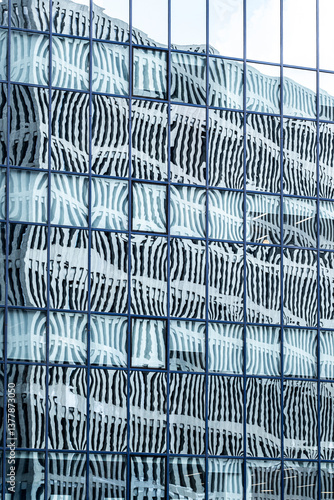 Patterned reflections on glass facade with warped symmetry and texture. Ideal for architecture, design or abstract urban stock themes with modern minimalism.