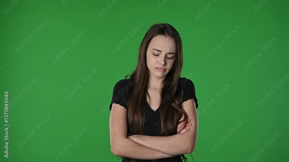 Teenage girl posing at camera with crossed arms and sad upset teary face, negative expression, isolated on chroma key green screen studio background mockup. Teenage girl posing at camera with crossed arms and sad upset teary face, negative expression, isolated on chroma key green screen studio background mockup.