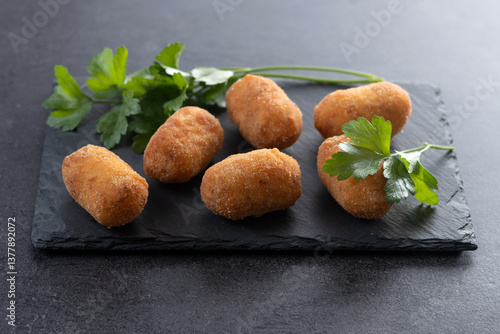 Bild auf Leinwand Fried cod croquettes on black slate background