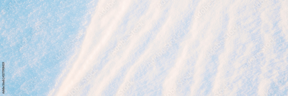 Wide panoramic winter background with snowy ground. Natural snow texture. Wind sculpted patterns on snow surface.