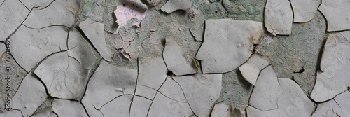 Obraz na płótnie Peeling paint on the wall. Panorama of a concrete wall with old cracked flaking paint. Weathered rough painted surface with patterns of cracks and peeling. Wide panoramic grunge texture for background w salonie