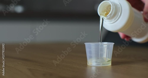 Man pours medical syrup into measuring cap. Medicine syrup bottle. Healthcare, people and Medicine concept. Close-up.