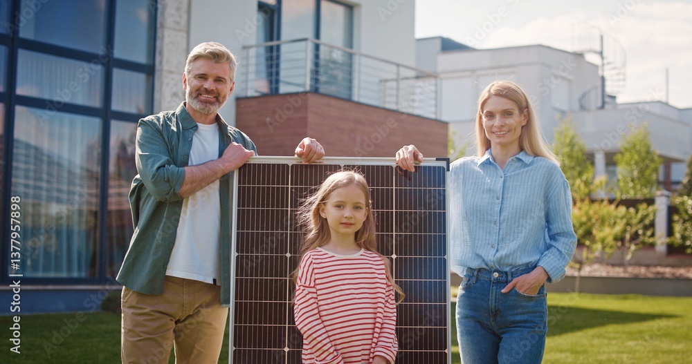Obraz premium Husband and wife talking about importance of green energy. Man and woman standing with solar panel. Children having fun at lawn and running around parents. Family of four eco conscious.