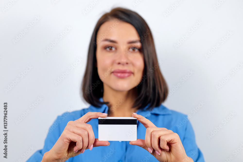 European brunette woman dressed in blue blouse holding laptop and plastic card with mockup European brunette woman dressed in blue blouse holding laptop and plastic card with mockup