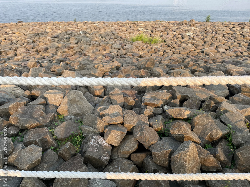 Obraz premium Beach with rock fragments and blue sky background with rope barrier