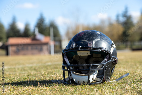 worn helmet, worn american football helmet and football field, grass and white lines, black helmet
