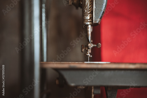 Closeup of the needle and mechanism of a vintage sewing machine with a blurred background.