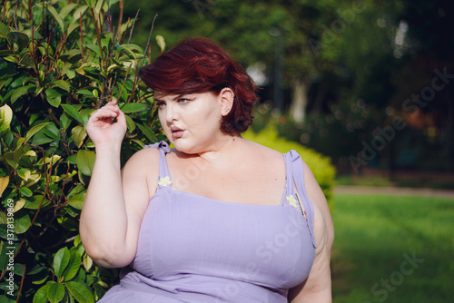 Glamorous young plus-size woman standing in a cool pose in the park