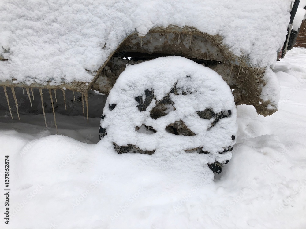 Rear wheel of a snow covered off-road vehicle SUV car parked outdoor on a winter ski slope