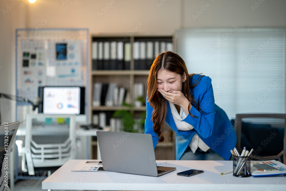 Obraz premium A woman is laughing while using a laptop in a cubicle