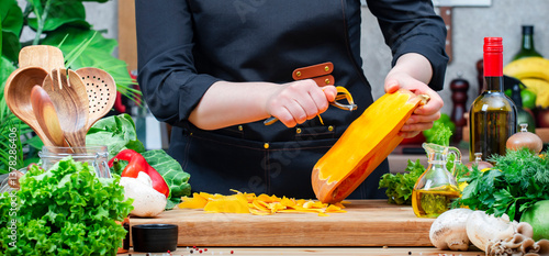 Foto Housewife peels pumpkin with vegetable peeler