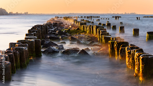 Fototapeta Naklejka Na Ścianę i Meble -  breakwater on the Baltic coast illuminated by the sun at golden hour.