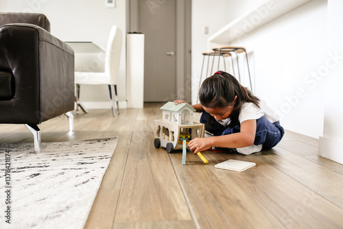 Young Asian girl playing with animals and a wooden truck ark on the floor