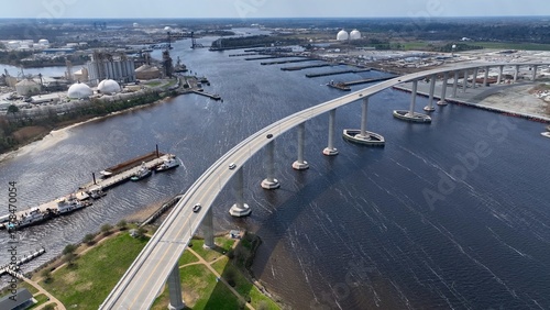 Cars crossing Elizabeth river at Norfolk Naval Shipyard in Portsmouth, Virginia showing industrial factories and other industries by the river with public park 