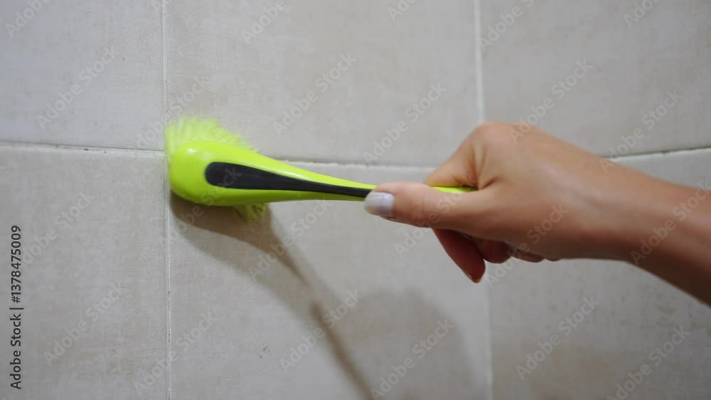 Woman applies special anti-mold antifungal agent to with brush, on grout between tiles covered with black mold in bathroom, close up. Fight against household mold, danger of mold to health