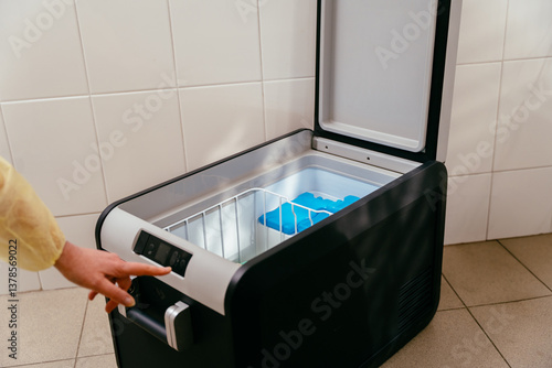 Fotografie Person adjusts settings on open medical freezer with ice packs inside