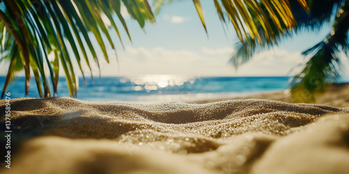 Obraz na płótnie Close-up of sand on a beach, with palm leaves framing the ocean in the background. w salonie