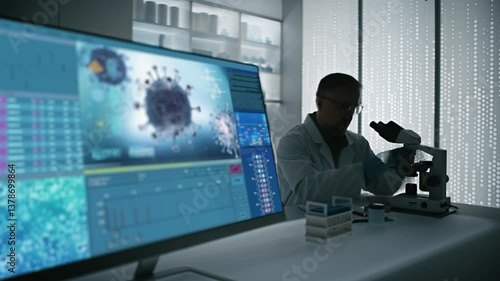 Male scientist in a lab coat working in a futuristic science laboratory with a microscope. Computer display showing the results of a vaccine on bacteria