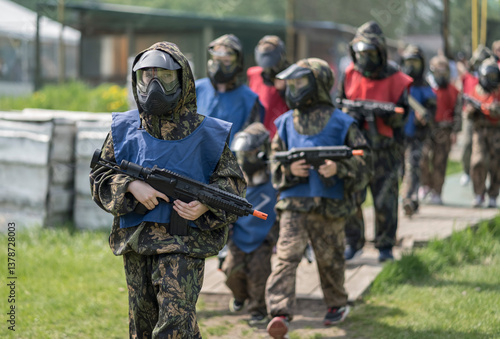 Kids playing airsoft. Team gun play on an outdoor sports field