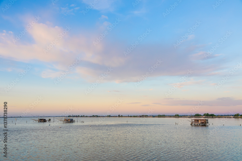 Italy, Comacchio lagoon. Panorama with traditional house for fishing at sunset, blue sky