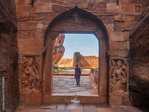 Obraz na płótnie Woman exploring ancient temple site at Badami. Tourist walking among ruins stone walls gateways in Karnataka, India w salonie