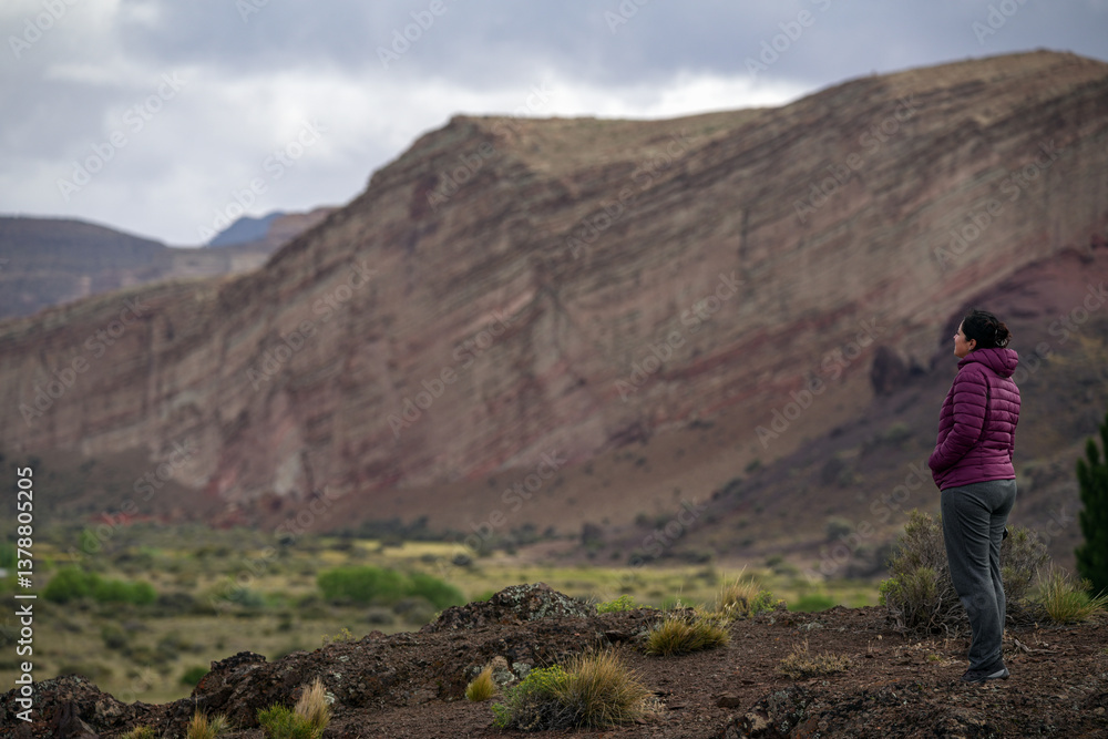 Naklejka premium Woman appreciating amazing sandstone landscape with big red cliffs. Los Altares, Chubut, Rio Negro